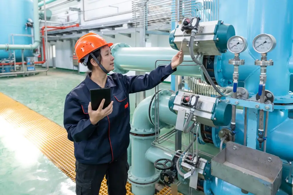 An Asian female engineer uses a tablet computer to record equipment in a chemical plant